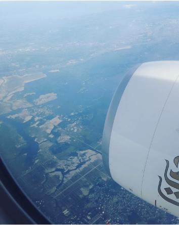 Looking out the window of a plane the viewer can see a town down below.