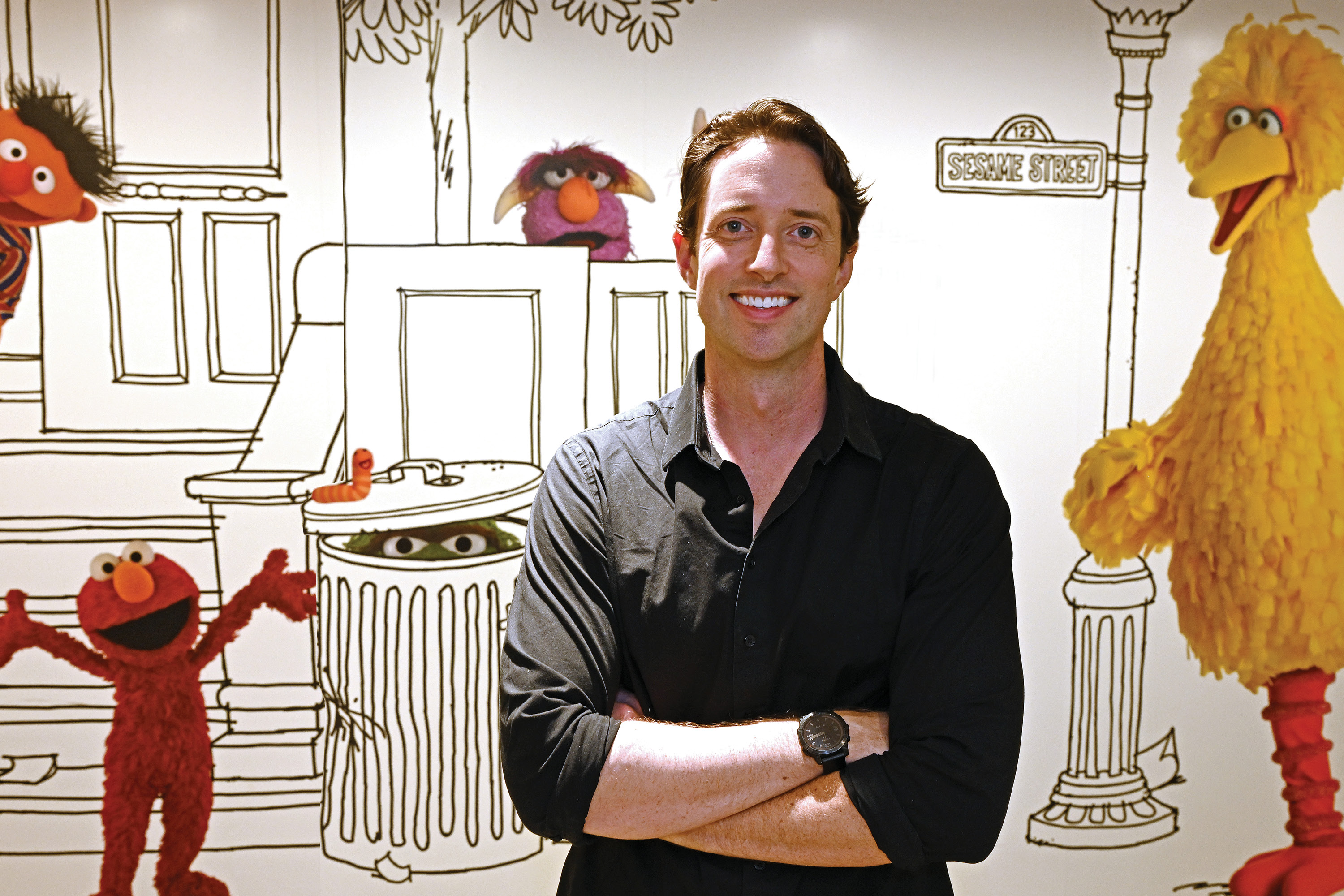 Image of TV producer Jordan Geary '04 in front of a large Sesame Street mural