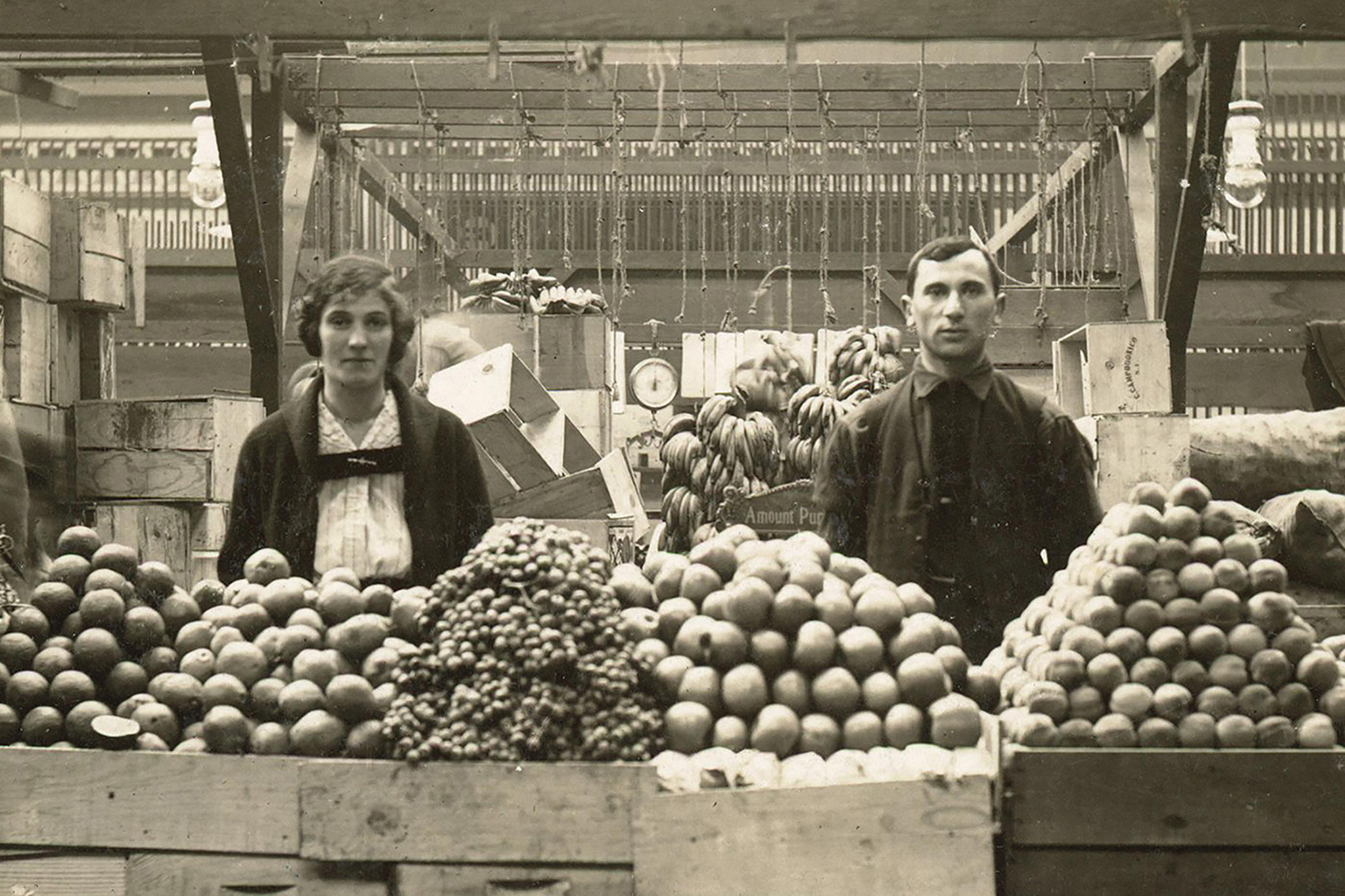 Historic image of early 20th century couple behind a fruit stand