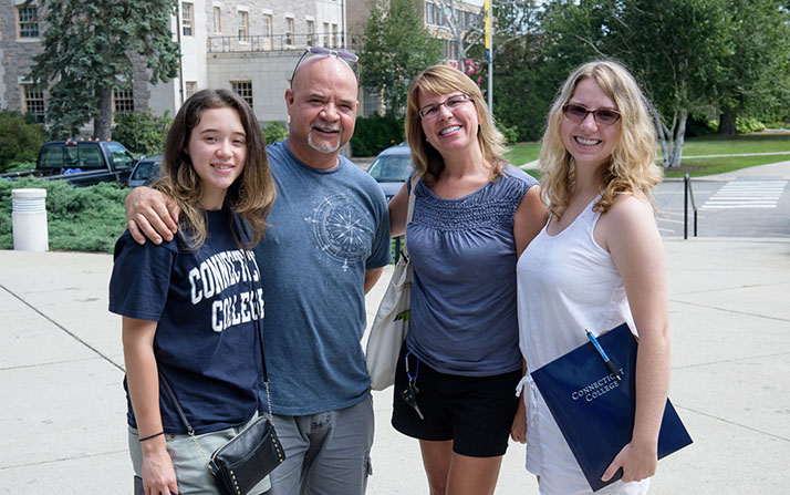 A member of the Class of 2021 poses with her family outside of one of the dorms. 