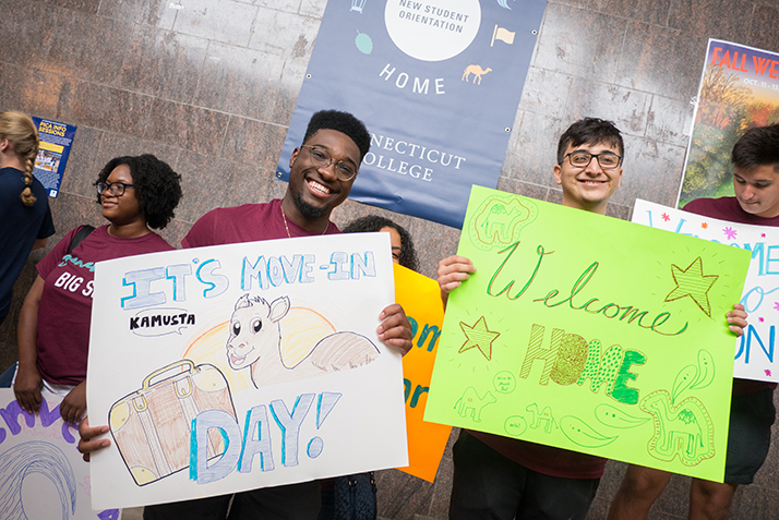 Students hold handmade signs welcoming the first year students.