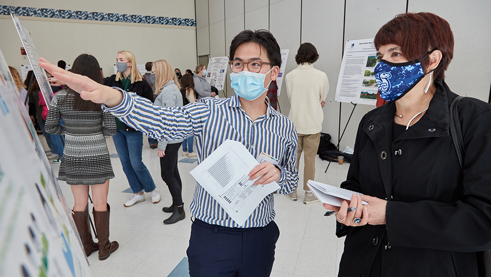 A student explains his poster to President Katherine Bergeron.