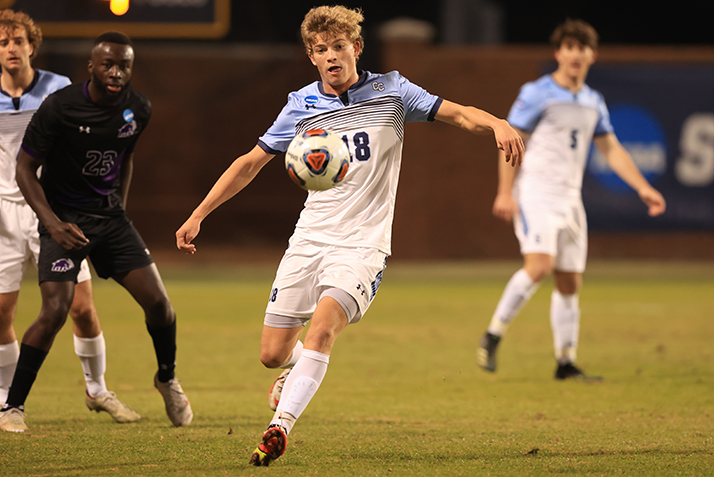 A player winds up to kick an airborne ball. 