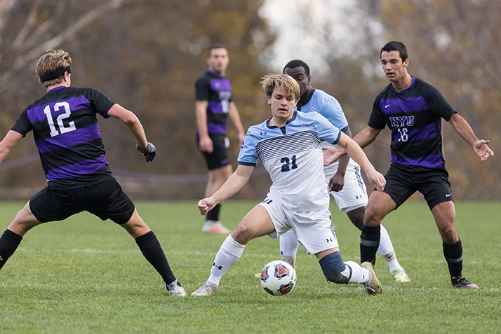 A Camel player keeps the ball away from NYU players.