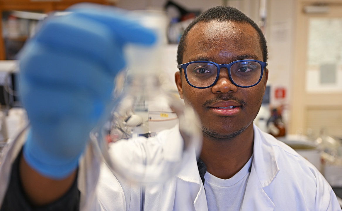 Admirabilis Kalolella ’23 inspects a beaker in the lab.