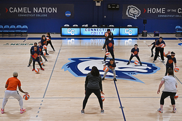 Morgan Tuck, Connecticut Sun Director of Franchise Development/Assistant General Manager, front center, Jenna Whelan ’22, Connecticut Sun Public Relations Intern,  front right, and Connecticut Sun guard Courtney Williams, front left, lead a ball handling drill for children from the Salvation Army Boys and Girls Club of New London