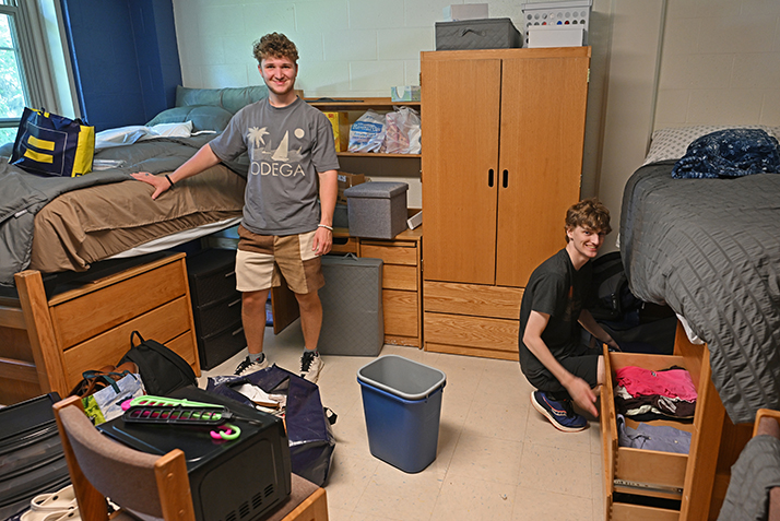 Roommates smile for a photo as they set up their new digs.