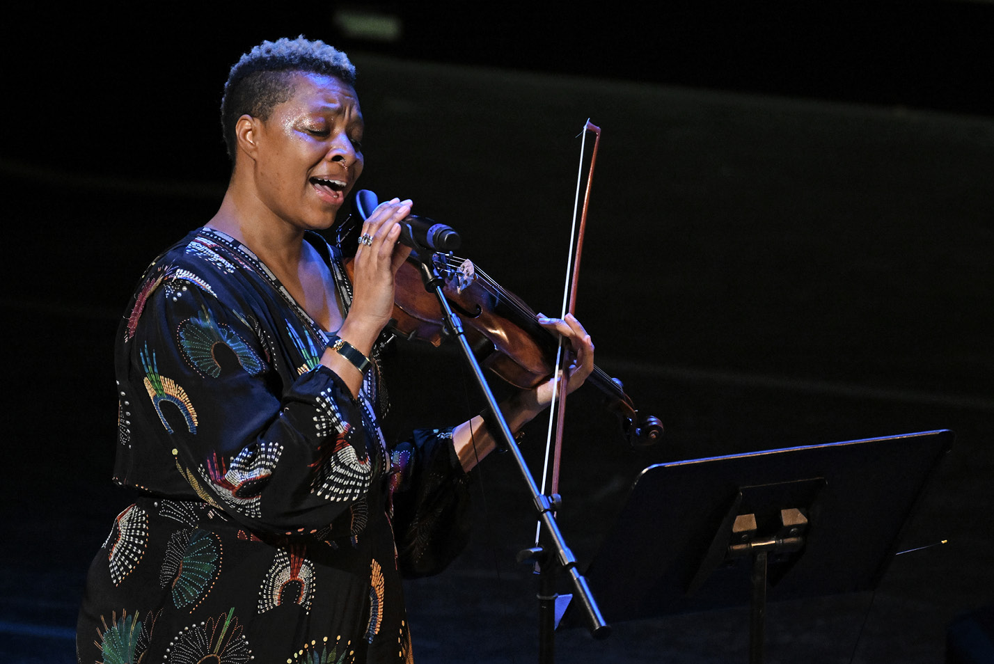 Woman singing in microphone holding violin