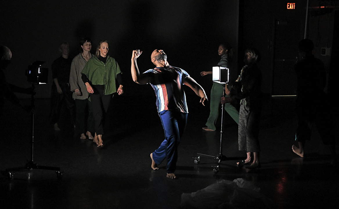 Modern dancers perform in dramatic lighting.