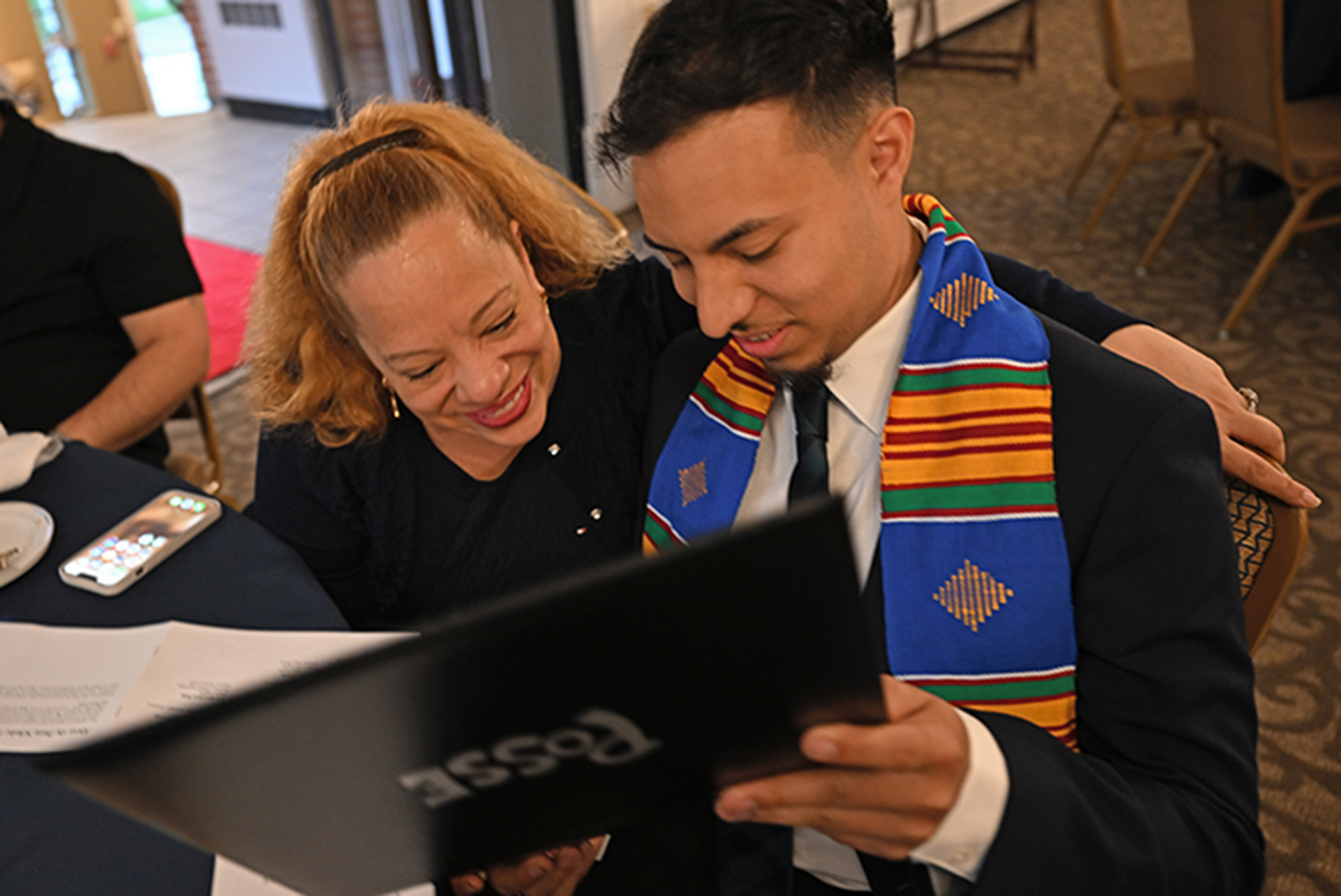 A student shows his mother an award certificate.