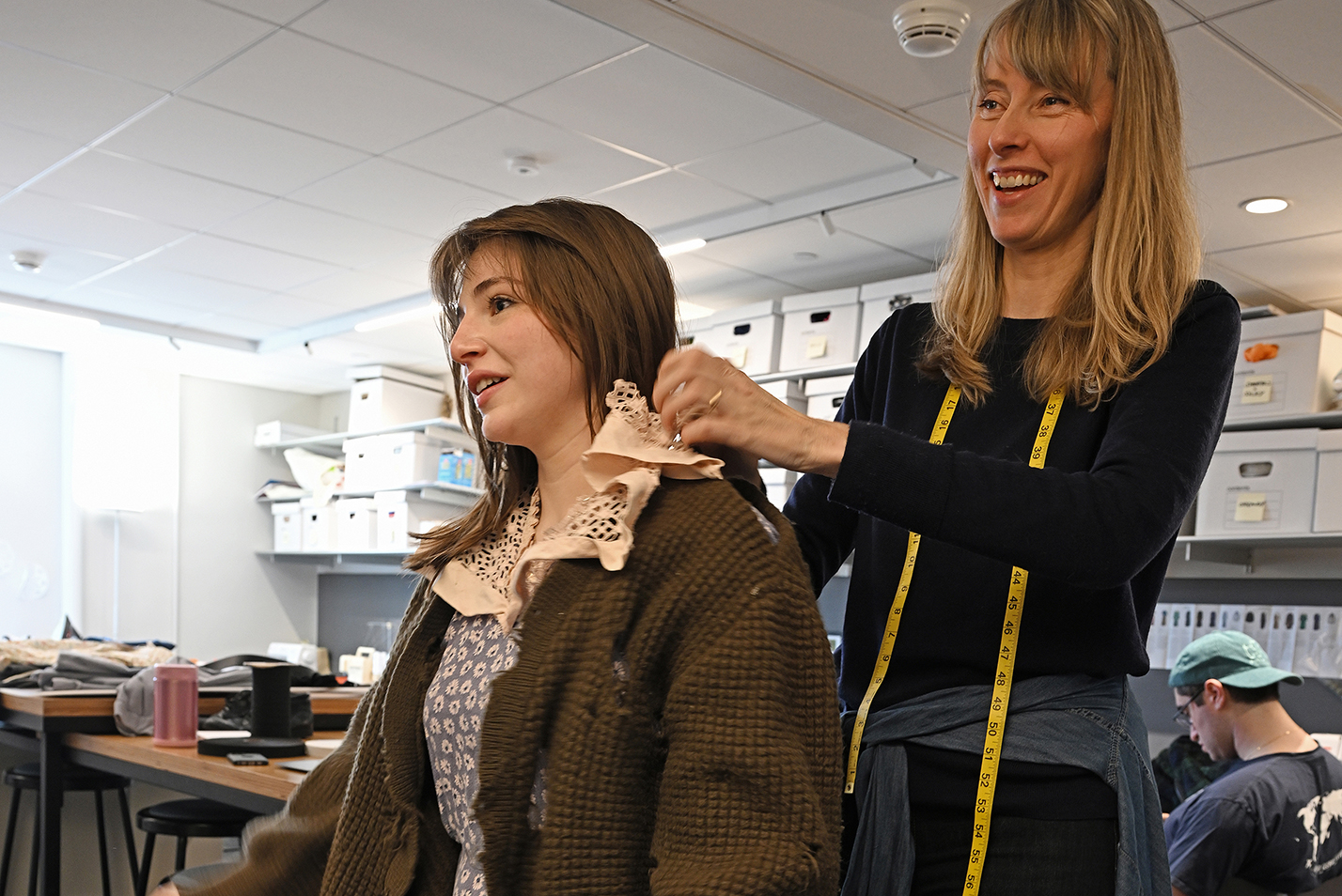 costumer works on collar of dress on actor