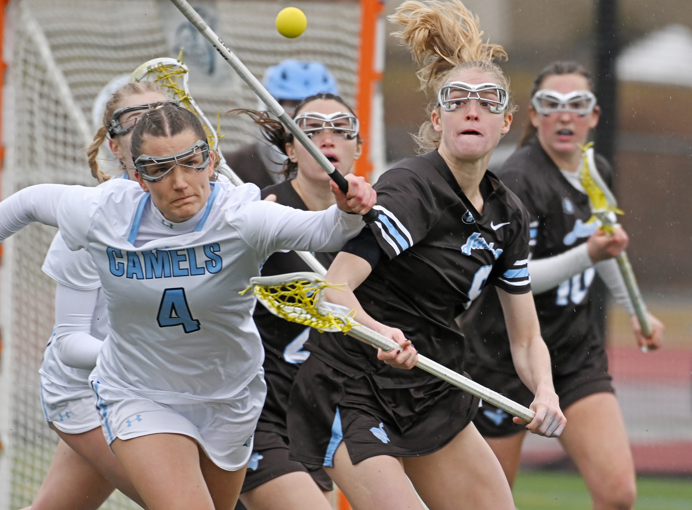 two female lacrosse players chase a ball in the air